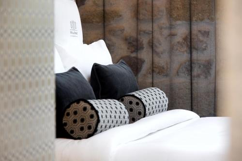 a bed with black and white pillows on it at Boutique Hôtel des Remparts & Spa in Aigues-Mortes