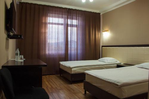 a hotel room with two beds and a window at Altamira Hotel in Karakol