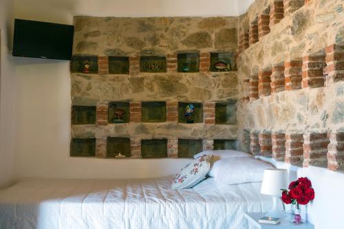 Cama en habitación con pared de piedra en The pigeon House, en Potamós
