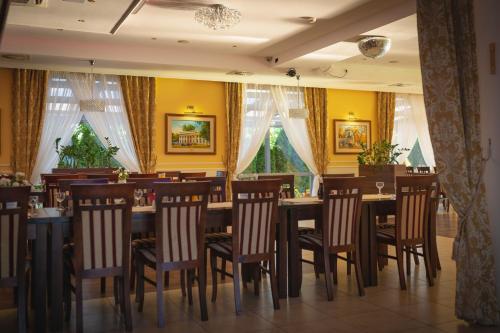 a restaurant with wooden tables and chairs and windows at Hotel Pikul in Puławy