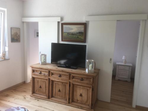 a living room with a flat screen tv on a wooden cabinet at Ferienhaus Menkhoff in Dornumersiel