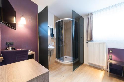 a bathroom with a walk in shower and a sink at Hotel Porta Nigra in Trier