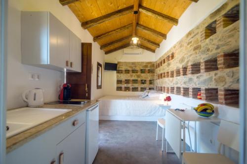 uma cozinha com armários brancos e uma cama num quarto em The pigeon House em Potamós