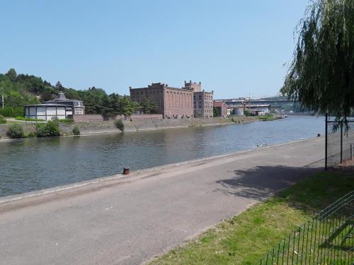a river with a road next to a river at Le Jardin du Thé Bord de la Meuse in Namur