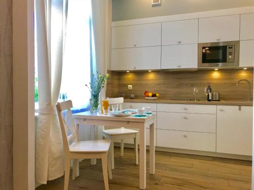 ソポトにあるInHome Sopot 2の白いキャビネット、テーブルと椅子付きのキッチンが備わります。