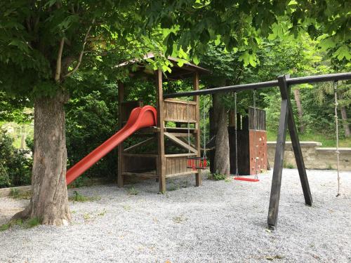 a playground with a red slide next to a tree at Hotel Restaurant Grünwalderhof in Innsbruck