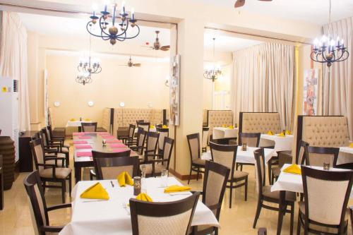 uma sala de jantar com mesas e cadeiras com guardanapos amarelos em Best Western Plus Accra Beach Hotel em Teshi