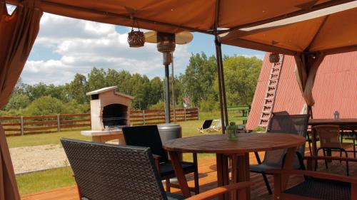 a table and chairs under an umbrella on a deck at Siedlisko Kępina Zdrój in Ostrów