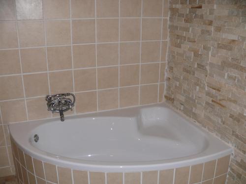 a bath tub in a tiled bathroom with a sink at 42onKing in Centurion
