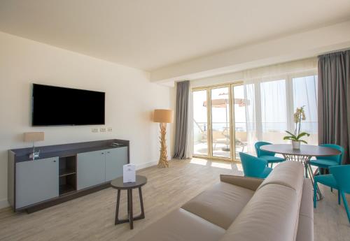 a living room with a couch and a tv at Les Terrasses d'Eze - Hôtel & Spa in Èze