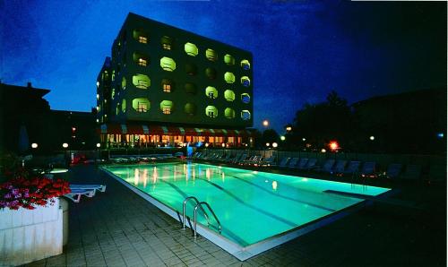 a swimming pool in front of a building at night at Hotel San Pietro in Cesenatico