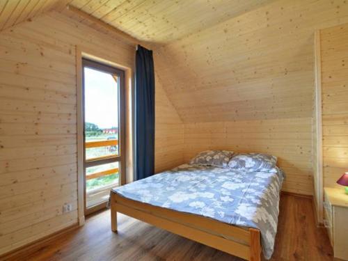 Bett in einem Holzzimmer mit Fenster in der Unterkunft Domki u Jagody in Sarbinowo