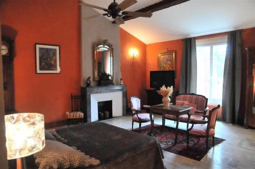 a living room with orange walls and a table and a couch at Domaine du Grand Malherbes in Aimargues