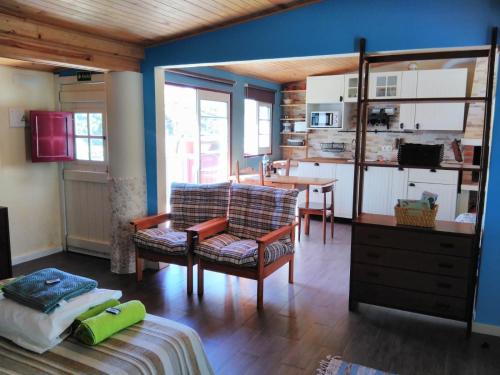 a living room with a couch and a chair and a kitchen at A Casinha da Baía in Porto Covo
