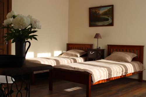 two beds in a room with a vase of flowers at Old Willows in Ventspils