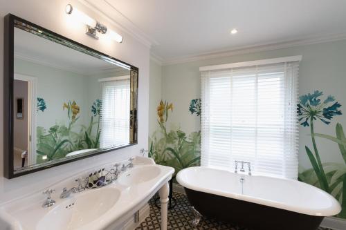 a bathroom with a tub and a large mirror at Gonville Hotel in Cambridge