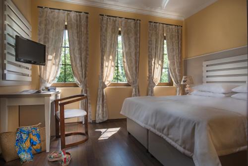 a bedroom with a bed and a desk and windows at Effect Boutique Villa Azzura - Adults Only in Nesebar