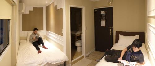 a couple of people sitting on beds in a room at May Rooms Taipei NTU in Taipei
