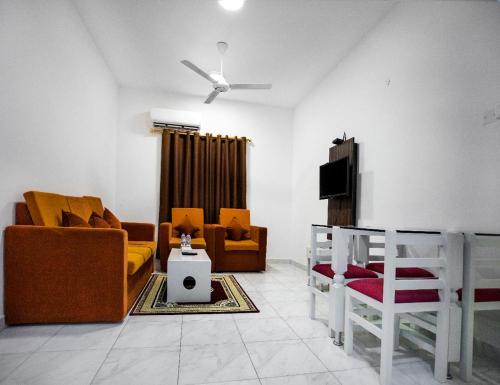 a living room with yellow and orange furniture and a ceiling fan at Star Emirates Inn Hotel Salalah in Salalah