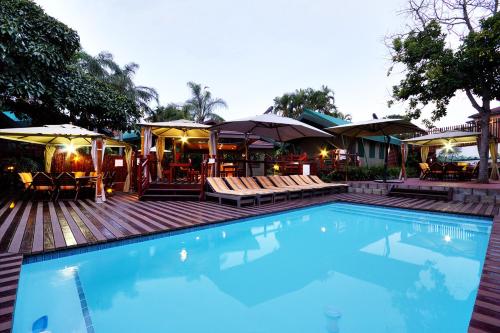 a swimming pool with chairs and umbrellas on a deck at Luxury Tented Village @ Urban Glamping in St Lucia