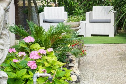 a garden with white chairs and pink flowers at B&B Pereuka in Rovigo
