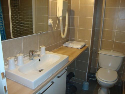 a bathroom with a sink and a toilet at Hôtel Au Petit Languedoc in Lourdes