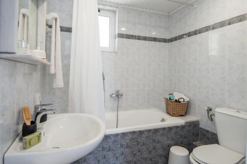 a bathroom with a tub and a sink and a toilet at Villas Margaris in Kalamaki