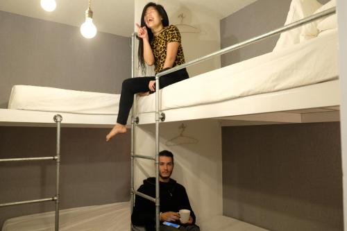 a woman is sitting on top of a bunk bed at May Rooms Taipei NTU in Taipei
