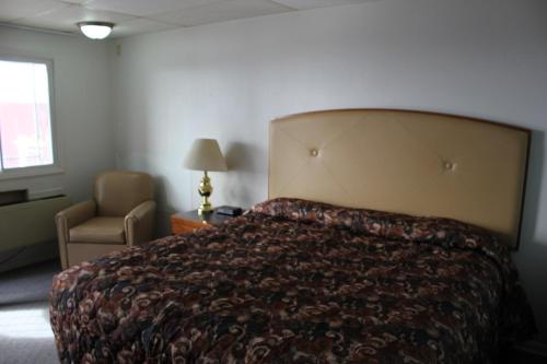 a bedroom with a bed and a chair and a window at Midlands Lodge in Hastings