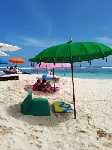 a green umbrella on a beach with people on it at Boutique hotel villa Cantik and karma beach club in Uluwatu
