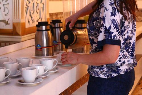 a woman is pouring coffee into cups on a counter at Spring Hotel in Novxanı