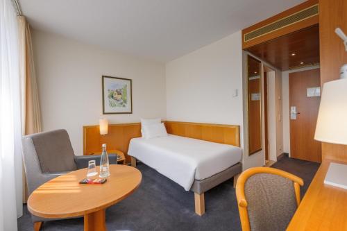 a small room with a bed and a table at Novotel Freiburg am Konzerthaus in Freiburg im Breisgau