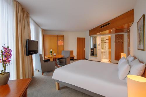 a hotel room with a white bed and a television at Novotel Freiburg am Konzerthaus in Freiburg im Breisgau