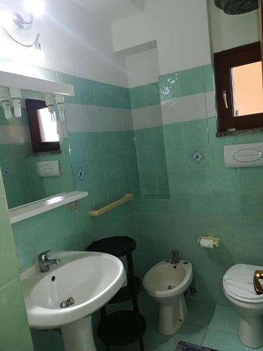 a green bathroom with a sink and a toilet at Stella Marina Budoni in Budoni