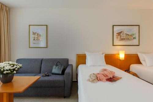 a hotel room with a bed and a couch at Novotel Freiburg am Konzerthaus in Freiburg im Breisgau