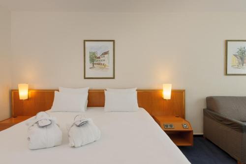 a hotel room with a bed with towels on it at Novotel Freiburg am Konzerthaus in Freiburg im Breisgau