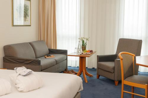 a hotel room with a bed and a couch and chairs at Novotel Freiburg am Konzerthaus in Freiburg im Breisgau