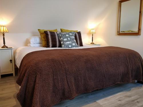 ein Bett mit einer braunen Decke und Kissen darauf in der Unterkunft "Balmoral View" in Ollach