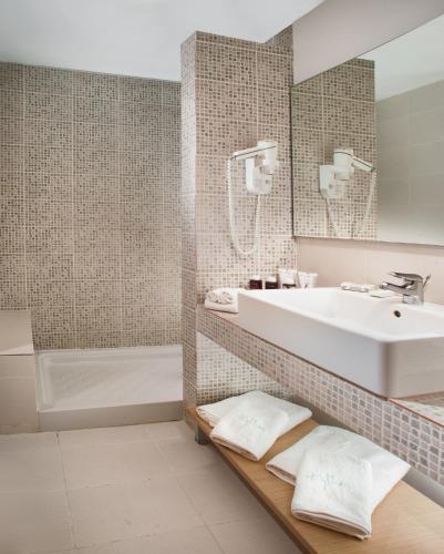 a bathroom with a white sink and a tub at Kythea Resort in Agia Pelagia