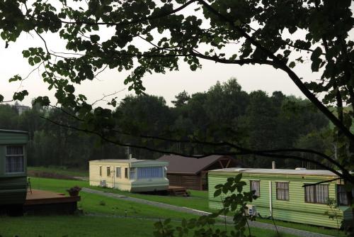 two mobile homes in a field with trees in the background at Leśny Zakątek Radocza in Radocza