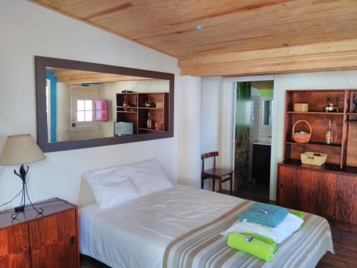 Schlafzimmer mit einem Bett und einem Spiegel an der Wand in der Unterkunft A Casinha da Baía in Porto Covo