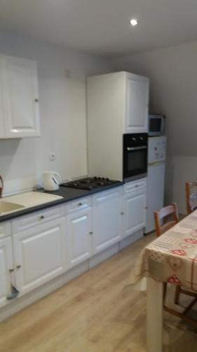 une cuisine avec des placards blancs et une table avec une table dans l'établissement Le Vivier appartement avec parking, à Boulogne-sur-Mer
