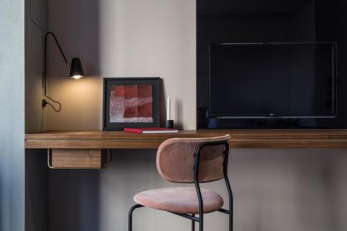 a desk with a chair in front of a television at Perianth Hotel, a Member of Design Hotels in Athens