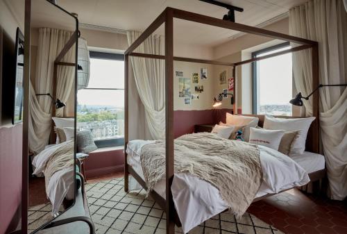 ein Schlafzimmer mit einem Himmelbett und einem großen Fenster in der Unterkunft 25hours Hotel Das Tour in Düsseldorf