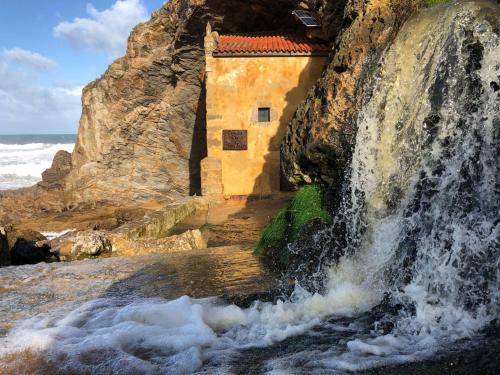 a building on a cliff next to a waterfall at Apartamentos Santillana del Mar in Santillana del Mar