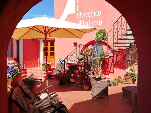 eine Terrasse mit einem Sonnenschirm, Stühlen und Blumen in der Unterkunft Hotel Il Vecchio Mulino in Àrbatax