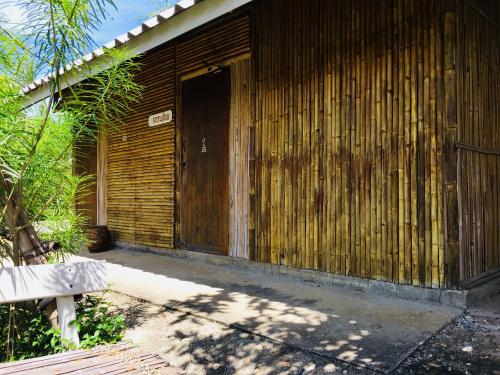 a wooden building with a door and a bench at Numpu Baandin in Sam Roi Yot