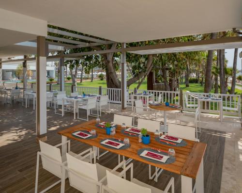 a patio with tables and white chairs and trees at Acanthus Cennet Barut Collection - Ultra All Inclusive in Side