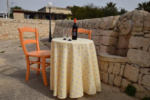 a table with a bottle of wine and two chairs at villa bove in Marina di Ragusa