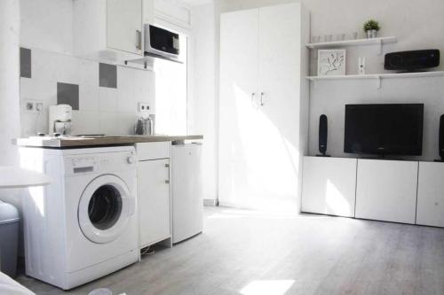 a white kitchen with a washing machine and a tv at GregBnb - Studio Terrasse - PARKING INCLUS - CLIMATISÉ - 15min Gare in Toulon